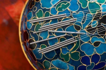 Acupuncture needles resting in a ceramic bowl