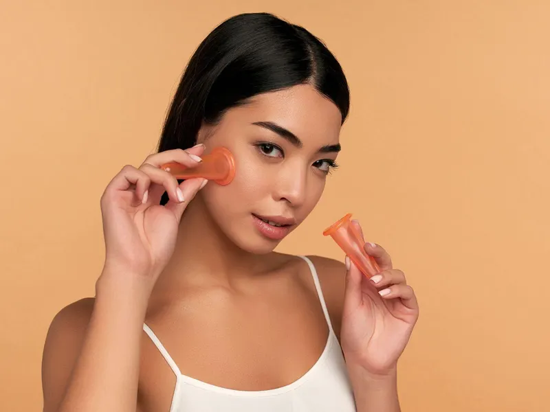 Woman holding two small facial cups against her cheek