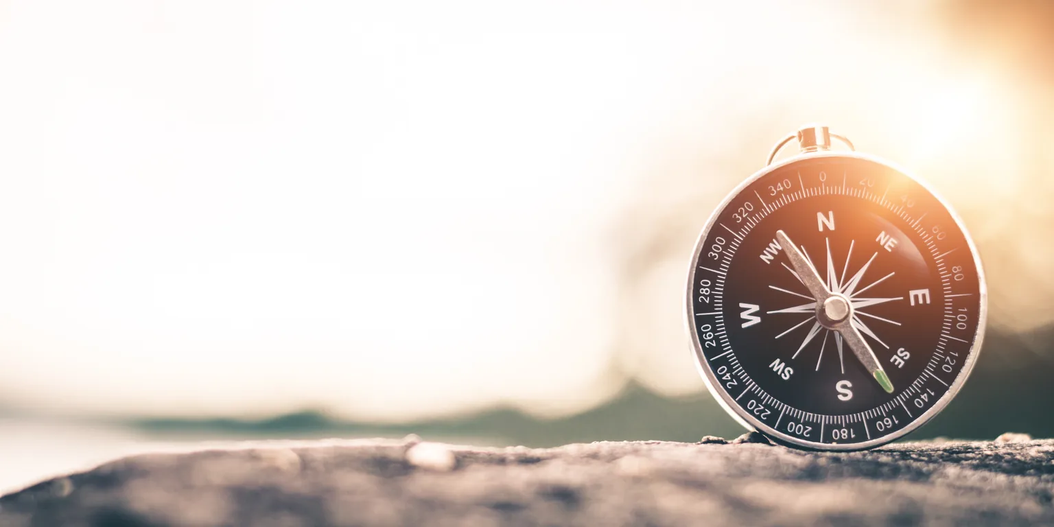 A compass resting on a rock in warm morning light